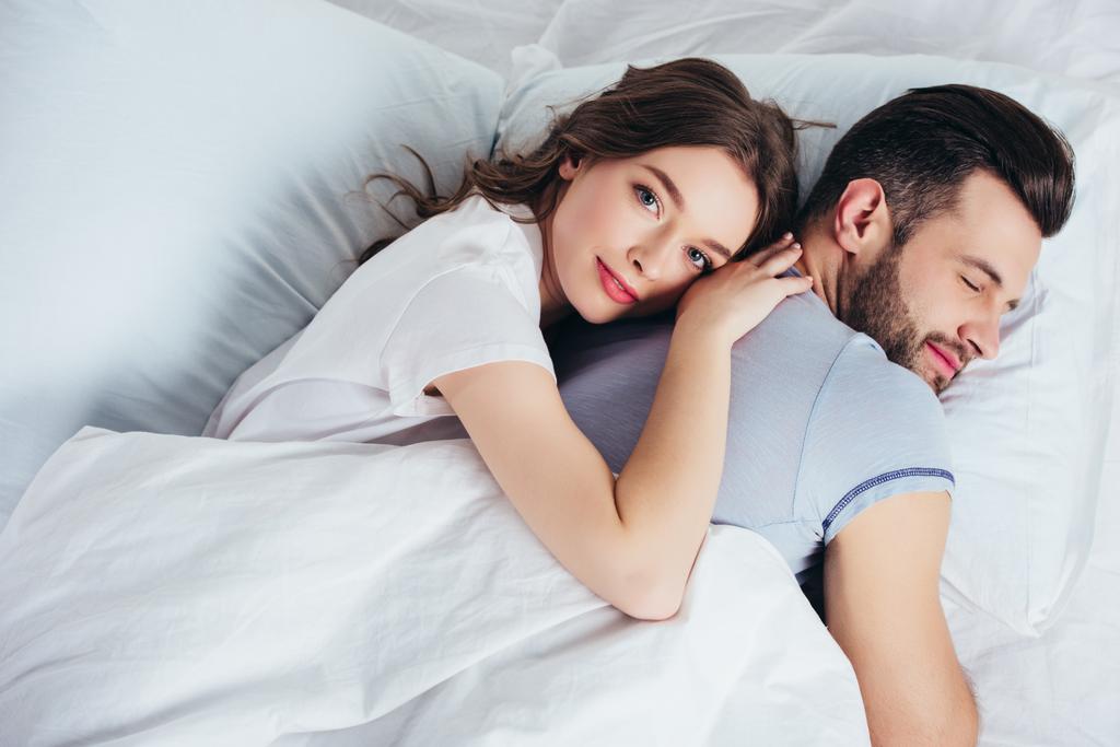jonge liefdevolle vriendin zachte omhelst vriend in bed - Foto, afbeelding