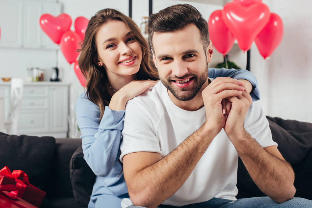 glückliches junges Paar feiert Valentinstag im Zimmer mit herzförmigen Luftballons - Foto, Bild