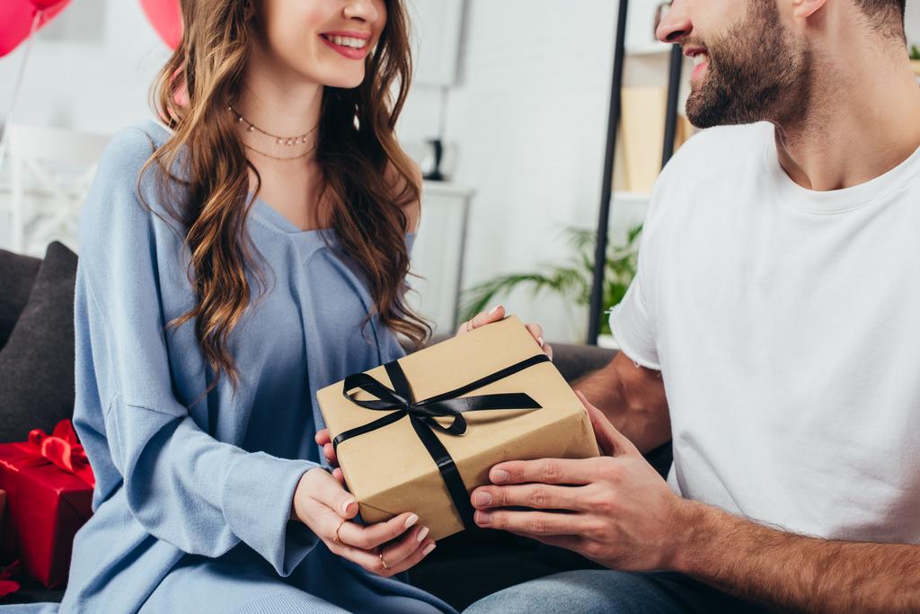 abgeschnittene Ansicht des jungen glücklichen Paares mit Geschenkbox mit Schleife - Foto, Bild
