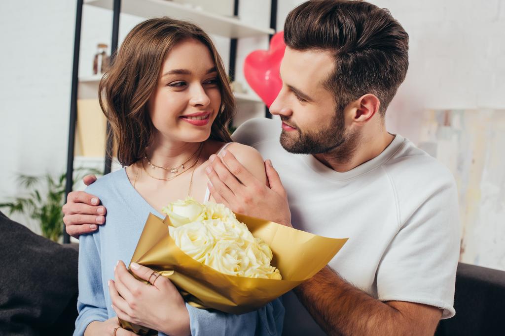 felice coppia che celebra San Valentino giorno mentre giovane uomo abbracciando fidanzata con bouquet di rose
 - Foto, immagini