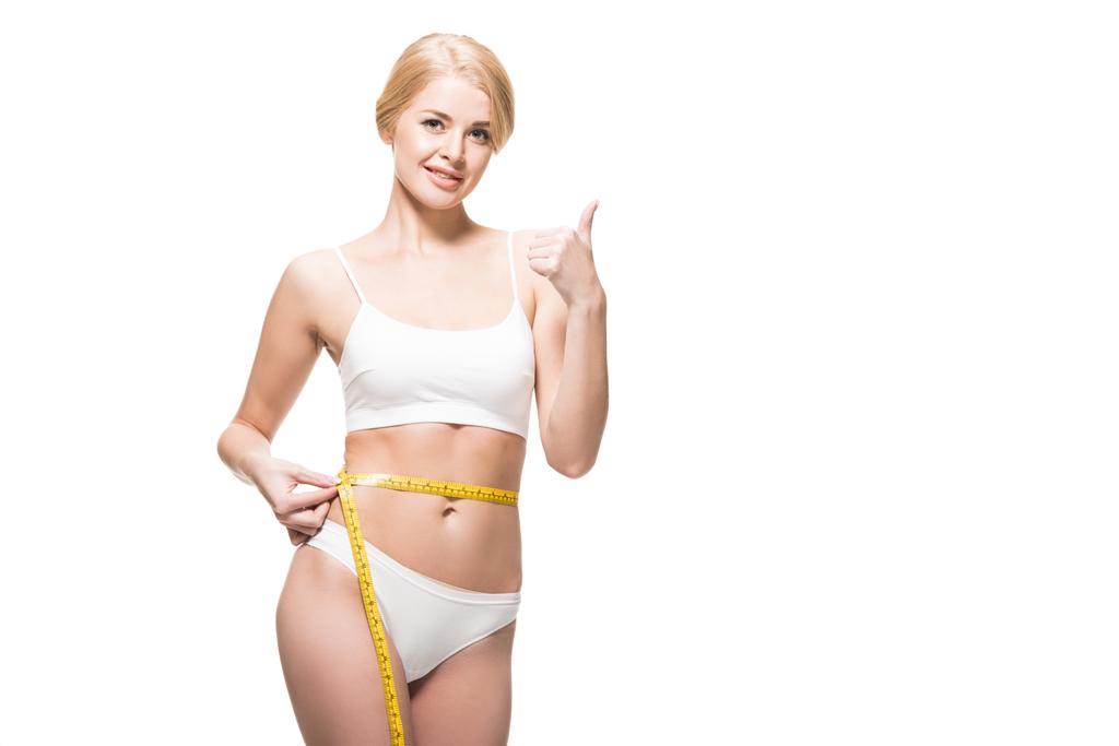 beautiful happy slim girl measuring waist with tape and showing thumb up isolated on white - Photo, Image