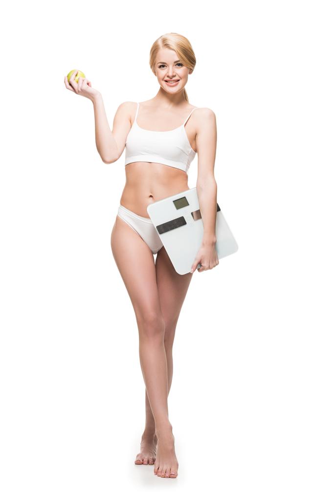 aantrekkelijke lachende meisje in ondergoed houden van apple en schalen geïsoleerd op wit - Foto, afbeelding