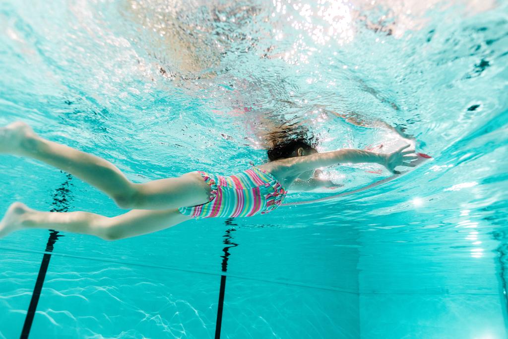 kid swimming in blue water in swimming pool  - Photo, Image