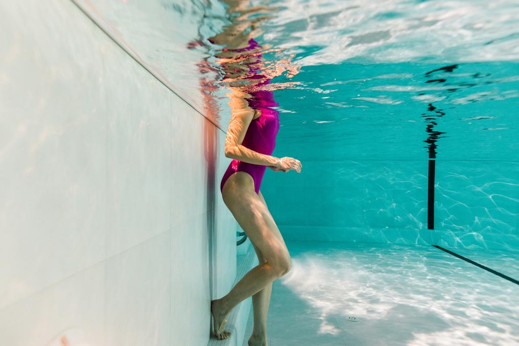 青い水の中の水着の女性を水中のトリミング ビュー - 写真・画像