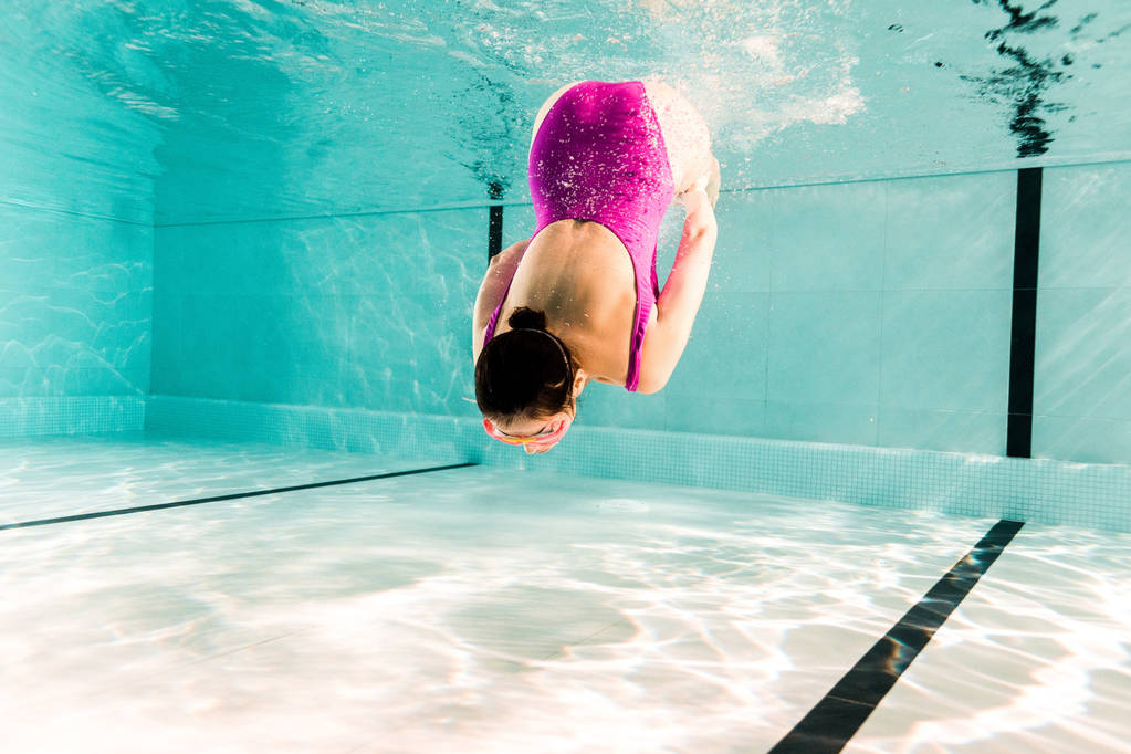 ピンクの水着姿の女性がスイミングプールで水中で ロイヤリティフリー写真 画像素材