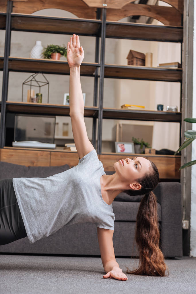 concentrated sportswoman doing side plank exercise at home  - Photo, Image