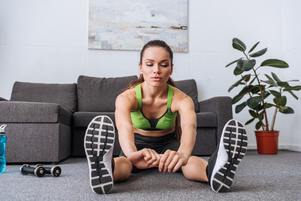 sportovkyně sedí a dělá protahovací cvičení doma - Fotografie, Obrázek