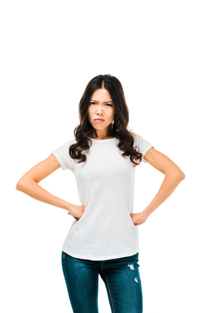 сердитая молодая женщина, стоящая с руками на талии и смотрящая на камеру, изолированную на белом
  - Фото, изображение