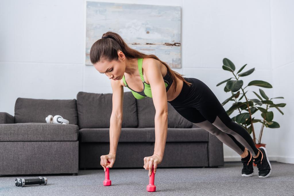 gericht Sportvrouw doet push ups met halters thuis - Foto, afbeelding