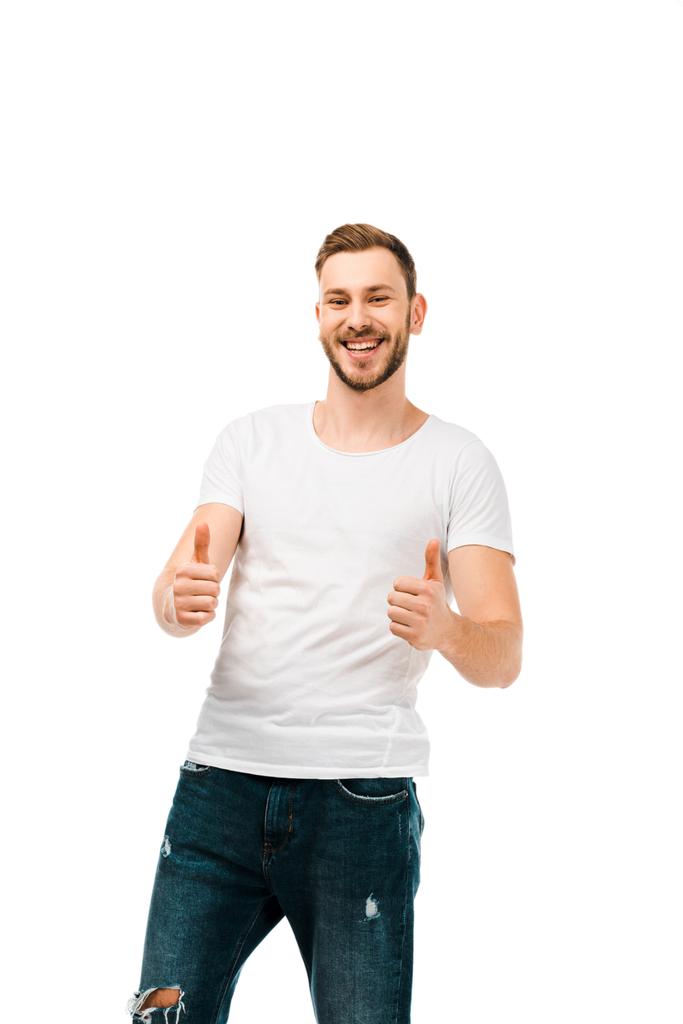 όμορφος ευτυχισμένος νέος δείχνει τους αντίχειρες επάνω και να χαμογελά στη φωτογραφική μηχανή που απομονώνονται σε λευκό - Φωτογραφία, εικόνα