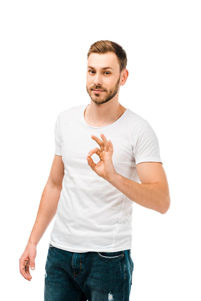 bello giovane uomo in bianco t-shirt mostrando segno ok e guardando la fotocamera isolata su bianco
 - Foto, immagini