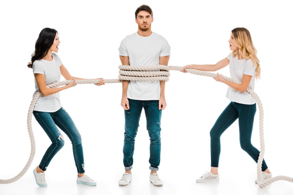 emotionele jonge vrouwen houden van touw rond jongeman geïsoleerd op wit   - Foto, afbeelding