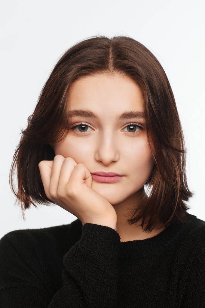 Ritratto di una bella adolescente in maglione nero su sfondo bianco. Capelli soffiati dal ventilatore
 - Foto, immagini