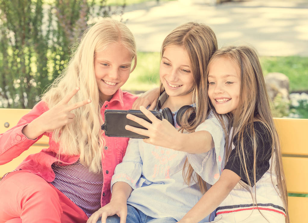 Les filles font selfie à l'extérieur tout en étant assis sur des longboards
 - Photo, image