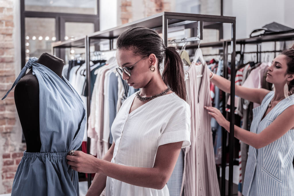 Dos asistentes trabajando en la boutique de moda colgando ropa de la nueva colección
 - Foto, Imagen