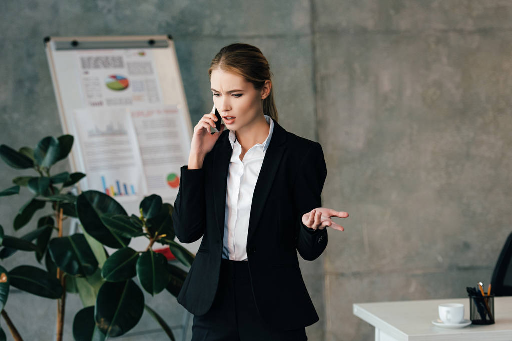 mujer de negocios seria hablando en el teléfono inteligente en la oficina
  - Foto, imagen