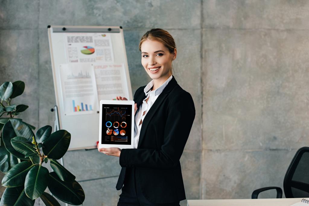 mujer de negocios sonriente sosteniendo tableta digital con diagramas en la pantalla
  - Foto, imagen