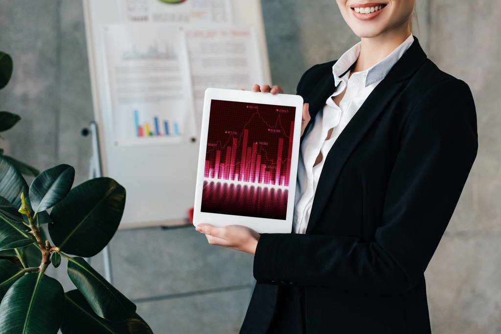 vista parcial de la mujer de negocios sonriente sosteniendo tableta digital con gráficos en la pantalla
 - Foto, imagen