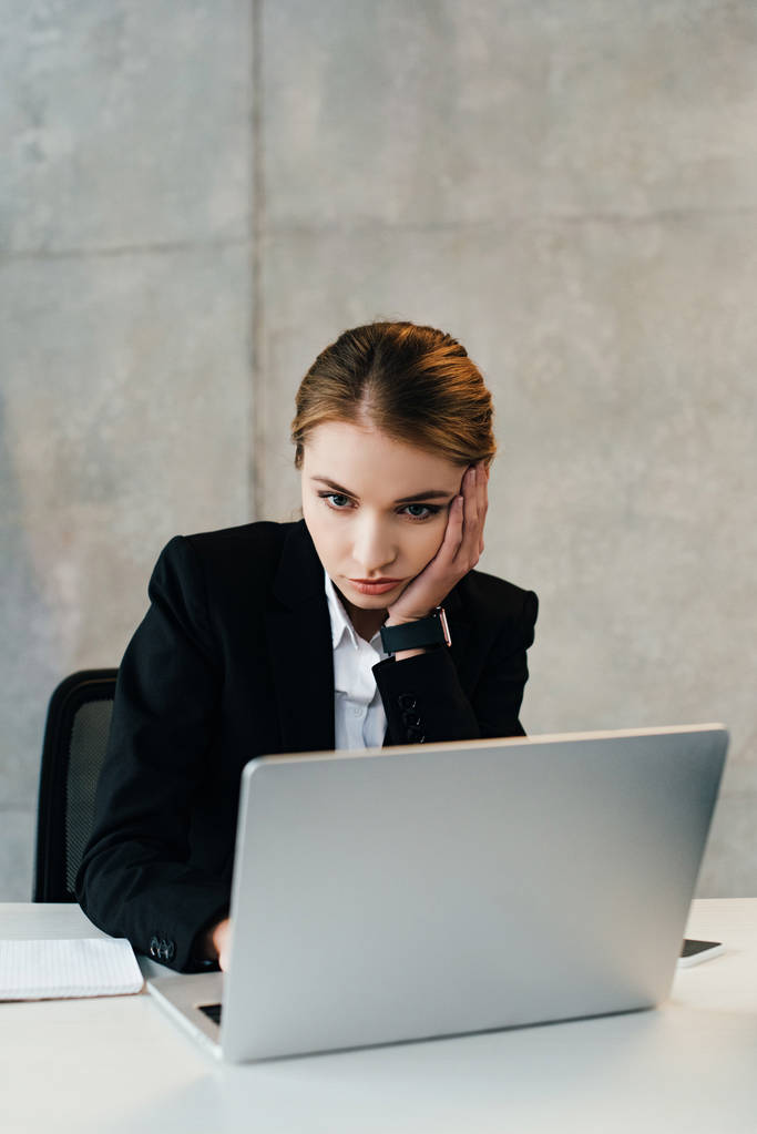 seria mujer de negocios concentrada usando el ordenador portátil, mientras que poner heand en la mano
 - Foto, Imagen