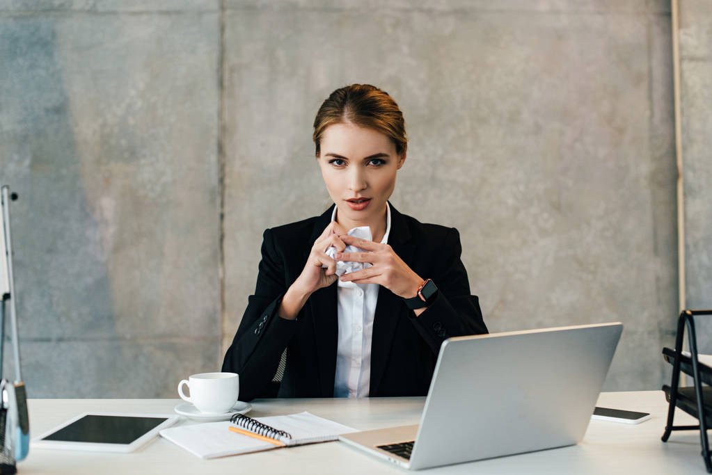 jolie femme d'affaires assise sur le lieu de travail avec du papier froissé dans les mains
 - Photo, image