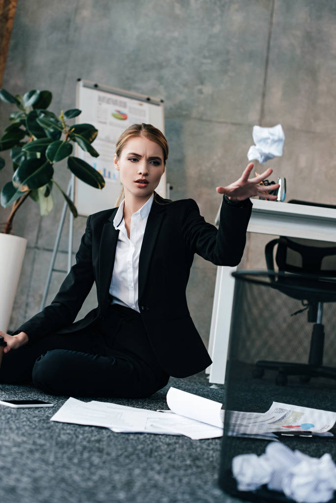 Geschäftsfrau sitzt auf dem Boden und wirft Serviette in den Korb - Foto, Bild