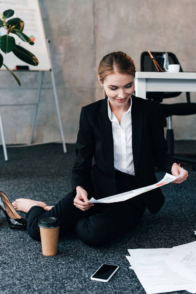 enfoque selectivo de la mujer de negocios descalza sentada en el suelo y el documento de lectura
 - Foto, imagen