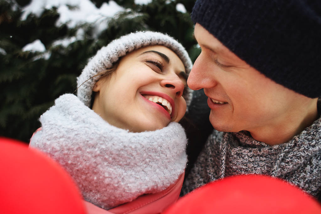 šťastný pár pÛdû v teplé zimní oblečení stojí venku s červený balónek ve tvaru srdce - Fotografie, Obrázek