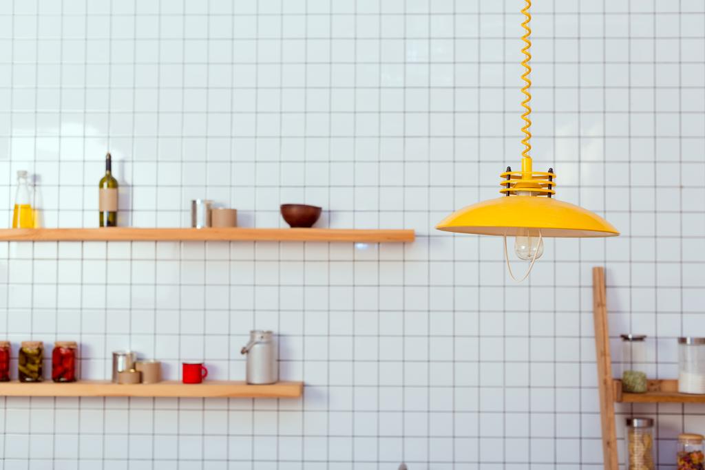 wooden shelves, jars and lamp in kitchen with white tile on background - Fotografie, Obrázek