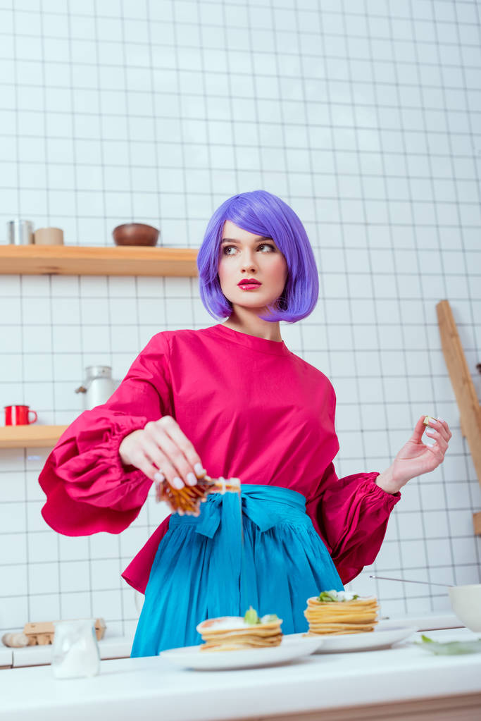 紫髪と台所でパンケーキにシロップを注ぐのカラフルな服を持つ主婦の選択と集中 - 写真・画像