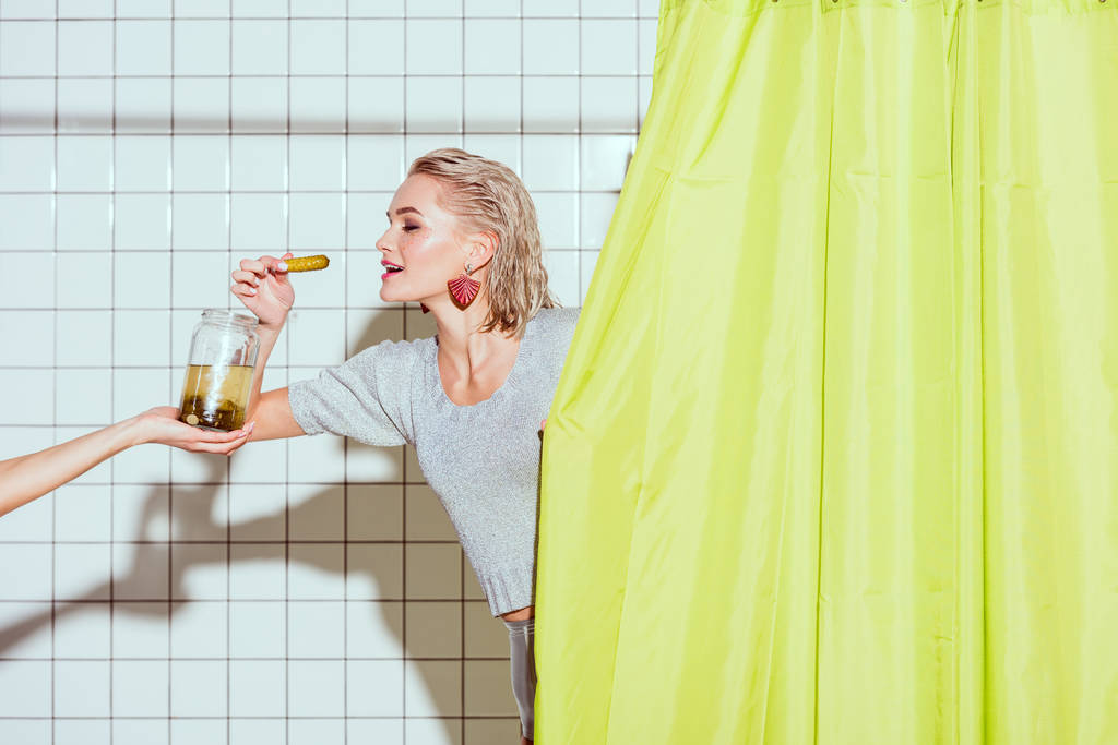 красива стильна жінка бере маринований огірок зі скляної банки в душі
 - Фото, зображення