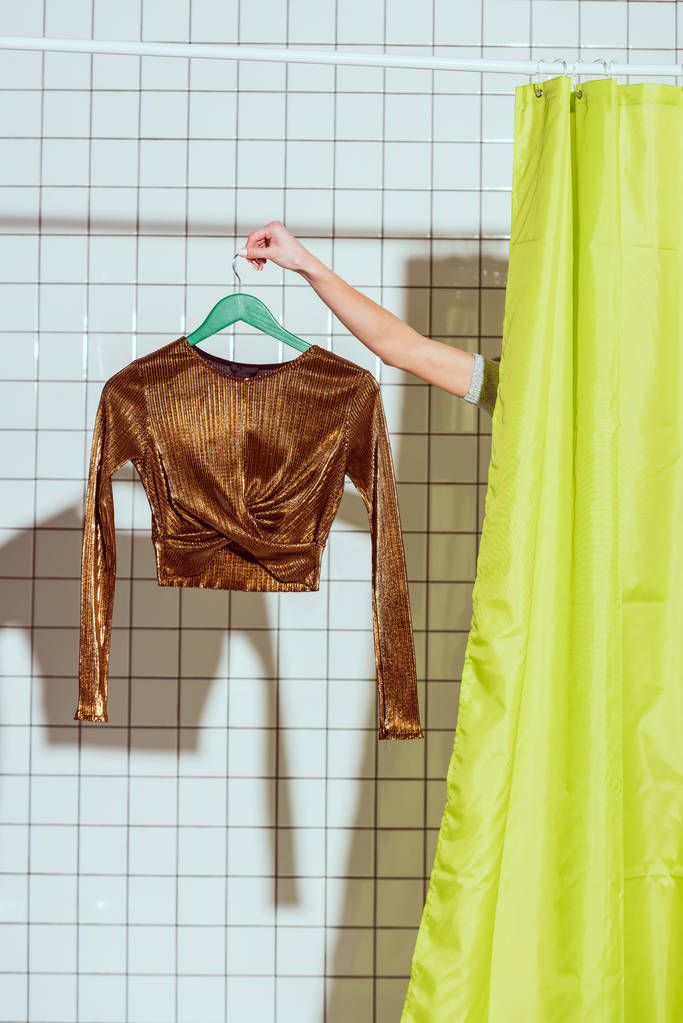 vista recortada de la mujer sosteniendo tapa de bronce en la percha en la ducha con cortina verde
 - Foto, imagen