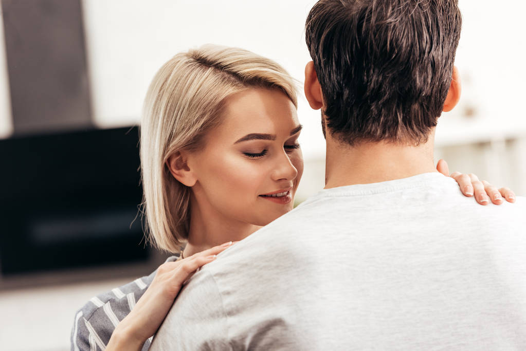 selective focus of boyfriend and attractive girlfriend hugging in kitchen - Photo, Image