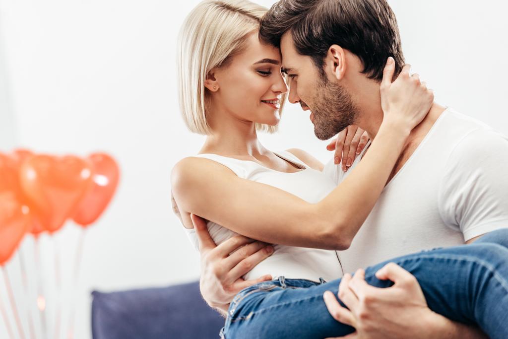 Selektivní fokus atraktivní přítelkyni a pohledný kluk drží a líbání doma na Valentýna - Fotografie, Obrázek