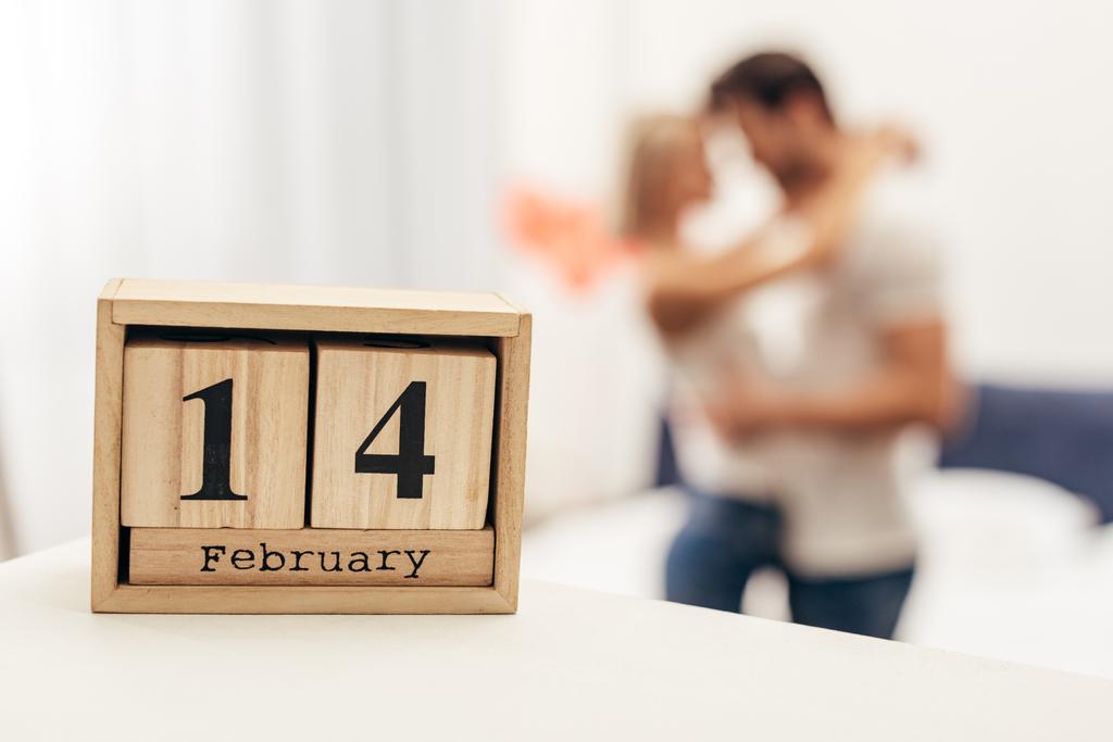 selective focus of wooden calendar with 14 february lettering and young couple on background on Valentines day - Photo, Image