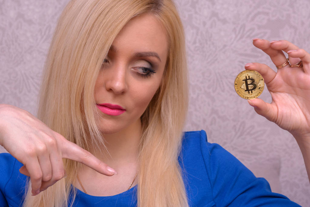 Χρυσή bitcoin στο χέρι του μια όμορφη ξανθιά κοπέλα με μπλε φόρεμα - Φωτογραφία, εικόνα