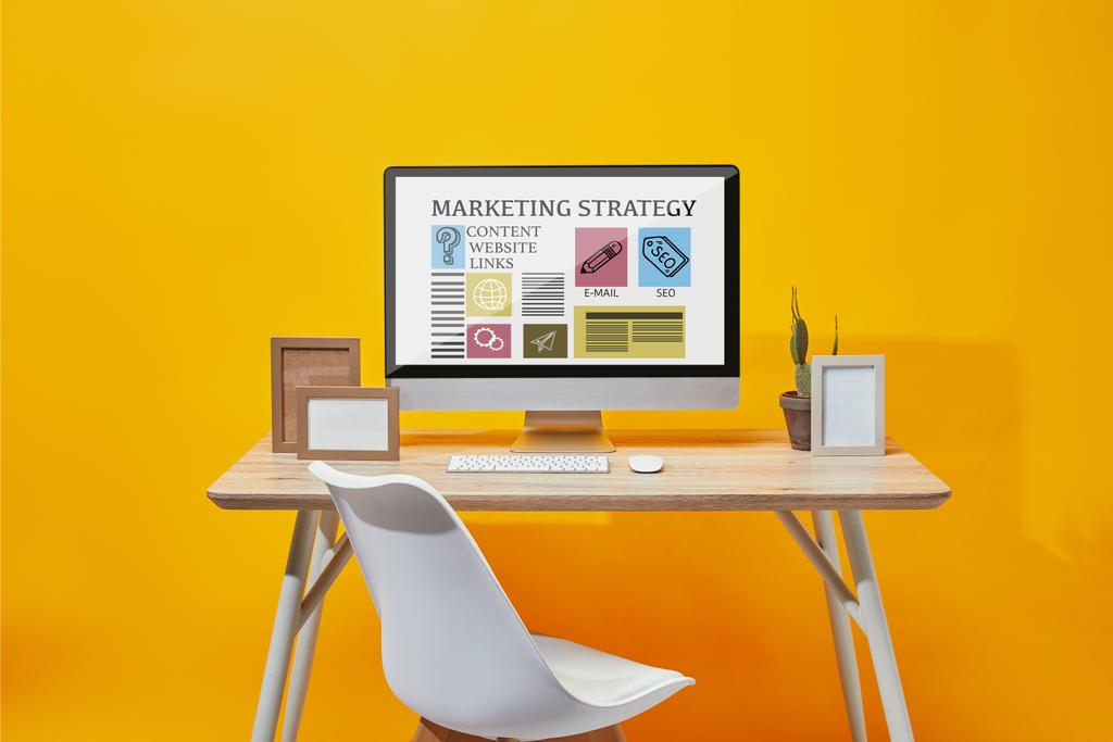 Computer mit Marketingstrategie-Website auf dem Bildschirm am Holztisch auf gelbem Hintergrund - Foto, Bild