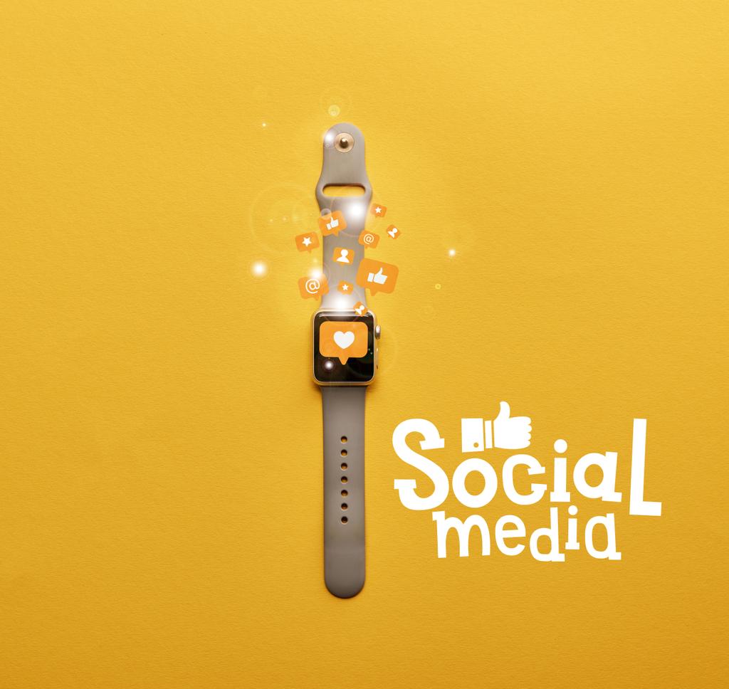アイコンと黄色表面にソーシャル メディア レタリング スマートウォッチの平面図  - 写真・画像