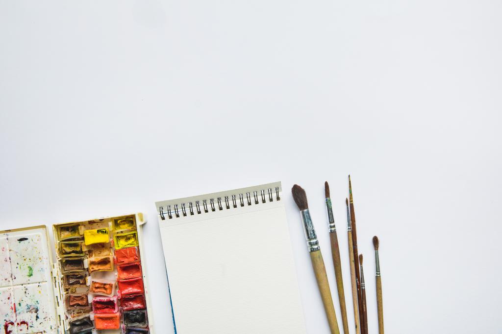 pohled shora na bílém pozadí s albem pro kreslení, vícebarevné barvy a štětce - Fotografie, Obrázek