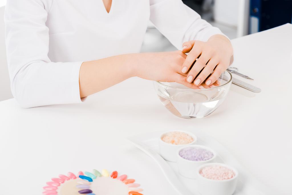 Cropped shot of manicurist in white uniform sitting at workplace - Photo, Image