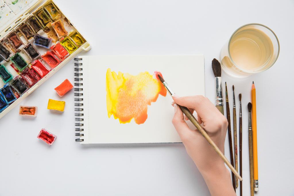 pohled shora ženských rukou kreslení v albu s akvarel barvy a štětec - Fotografie, Obrázek