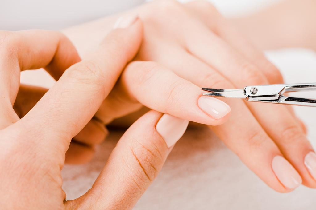 Vista cortada de manicure usando tesoura de manicure para remover cutícula
 - Foto, Imagem
