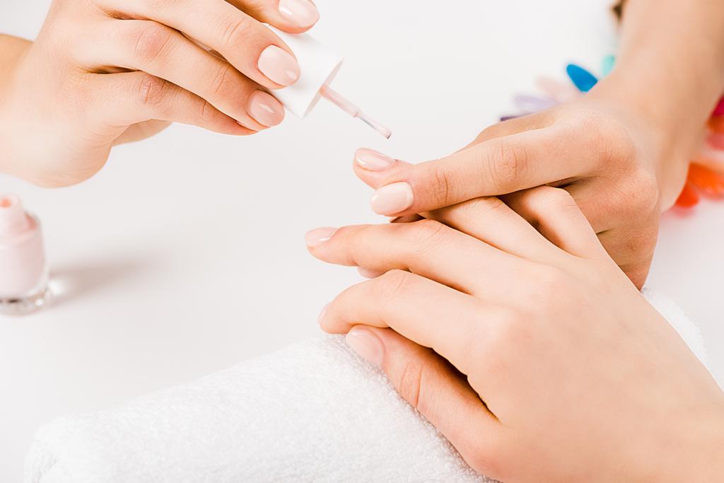 Gedeeltelijke weergave van manicure zachtjes hand houden tijdens het toepassen van nagellak - Foto, afbeelding