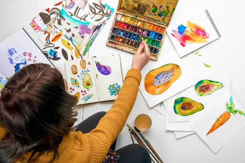 το top view γυναίκα γυναίκες αναμιγνύοντας χρώματα watercolor, ενώ περιβάλλεται από τα σχέδια χρώματος - Φωτογραφία, εικόνα