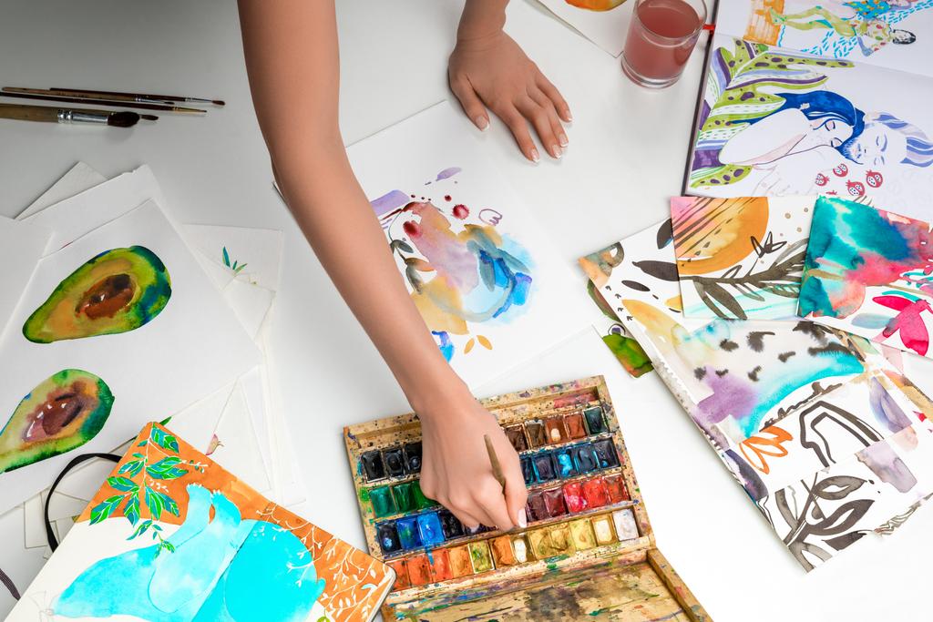 enfoque selectivo de las manos femeninas mezclando pinturas de acuarela rodeadas de imágenes en color
 - Foto, imagen