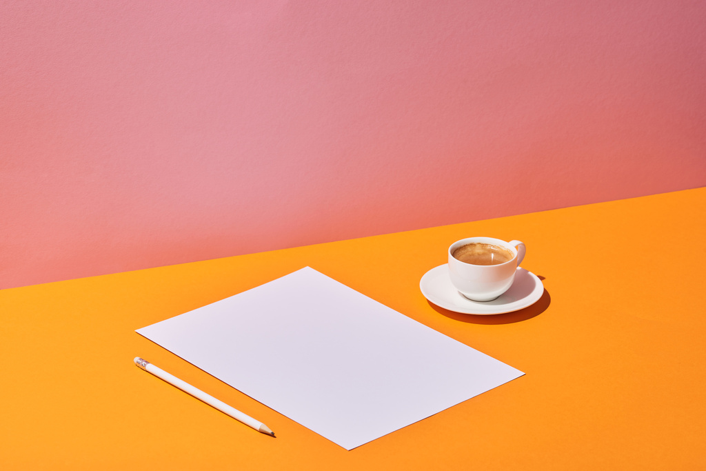 paper sheet, pencil and coffee cup on yellow desk and pink background - Photo, Image