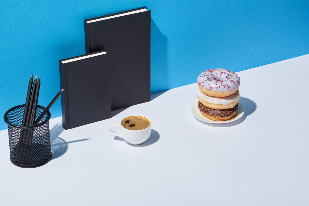 savoureux beignets, tasse à café, porte-crayon et cahiers sur fond blanc et bleu
 - Photo, image