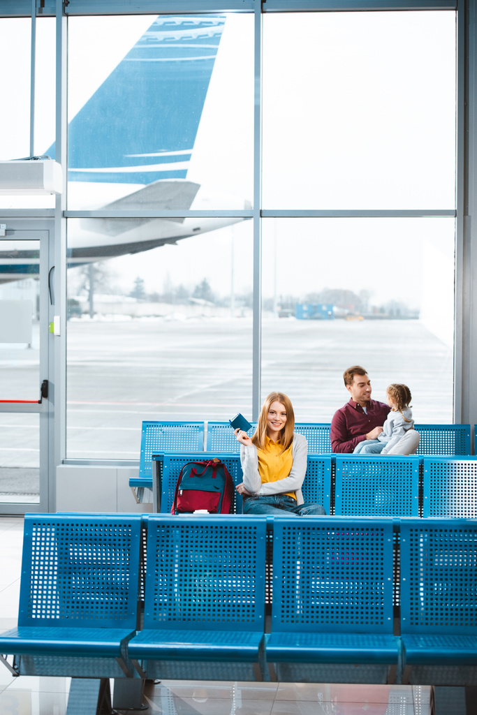 attraktive Frau mit Pass und Flugticket mit Menschen im Hintergrund  - Foto, Bild