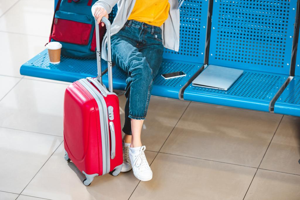 bijgesneden beeld van vrouw met bagage in de buurt van rugzak laptop en smartphone  - Foto, afbeelding