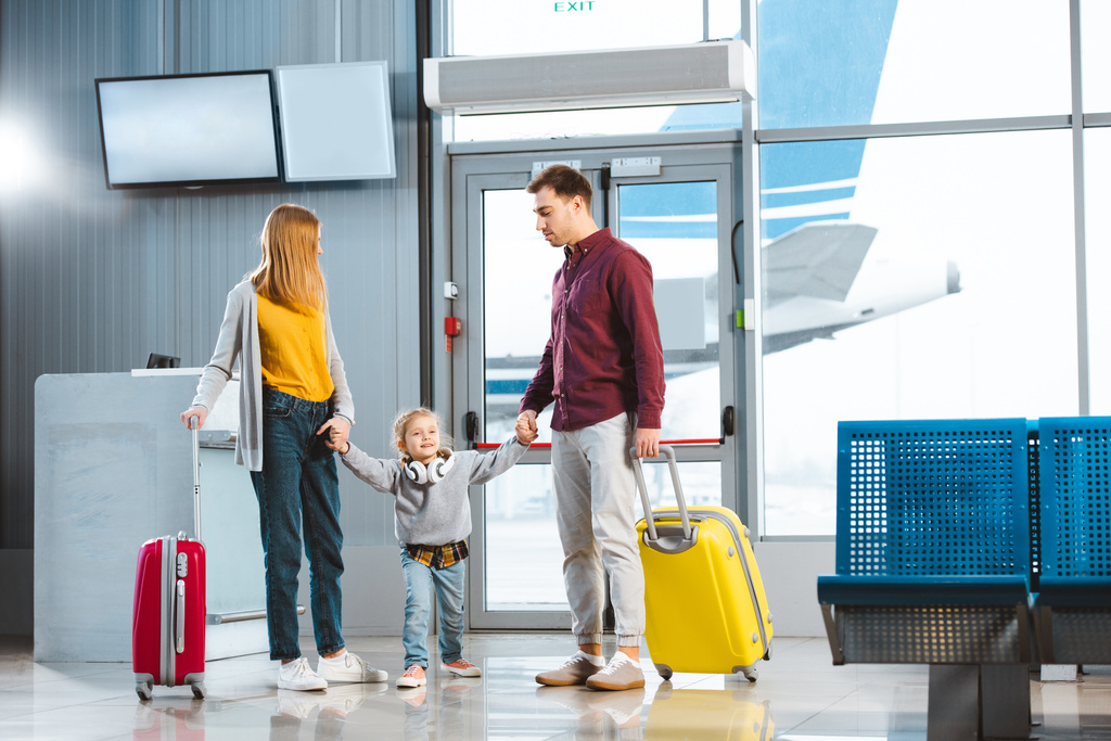 manželka a manžel drží za ruce s dcerou a stojí elegantní kufry v Letiště - Fotografie, Obrázek
