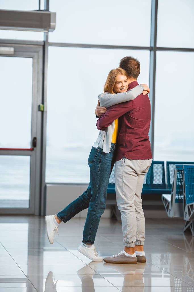 aantrekkelijke vrouw knuffelen vriendje in wachten hall  - Foto, afbeelding